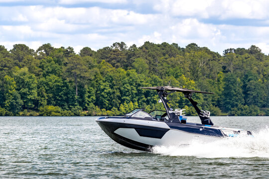 Boater on blue wakeboard wake boat enjoying summer day on freshwater lake.