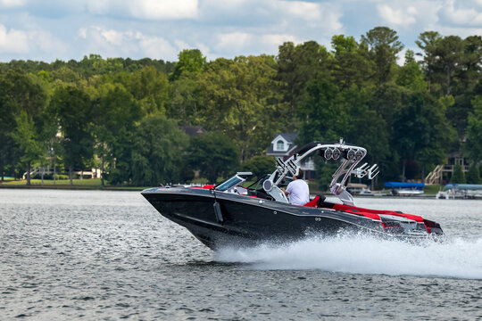 Boater on gray wakeboard wake boat enjoying summer day on freshwater lake.