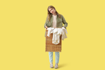 Tired young woman with laundry basket on yellow background
