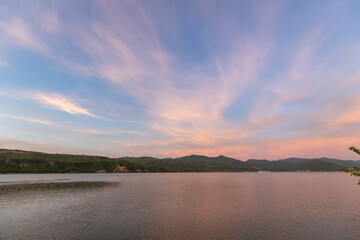 sunset scene over a calm lake with a mountain range in the distance, reflecting the warm colors of the sky and the serenity of the natural environment