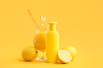 Bottle of sunscreen cream, glass of juice and lemons on color background