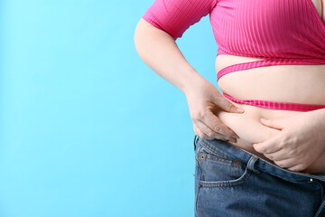 Overweight woman in tight clothes on blue background, closeup. Diet concept
