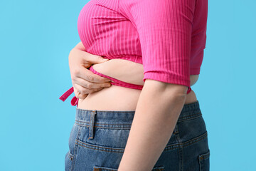 Overweight woman on blue background, closeup. Diet concept