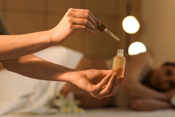 Massage therapist with oil for pregnant woman in spa salon, closeup