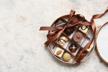 Box with chocolate candies on light background