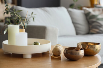Tibetan bowls with wooden balls and candles on table in living room, closeup