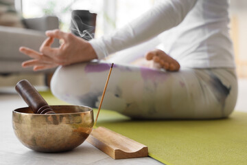Aroma stick with Tibetan bowl of sporty woman practicing yoga at home, closeup - Powered by Adobe
