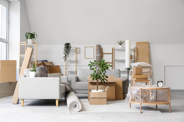 Grey sofa, coffee table and cardboard boxes in light living room on moving day