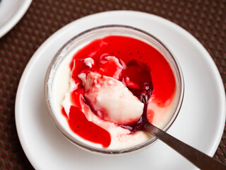 Delicious Italian creamy vanilla panna cotta with layer of cranberry jam served in glass bowl....