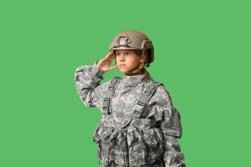 Portrait of teenage soldier saluting on green background