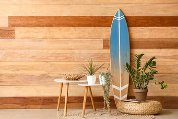 Houseplant, coffee table and surf board near wooden wall in stylish room