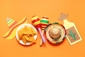 Mexican maracas with sombrero, nachos and decor on orange background. Cinco de Mayo