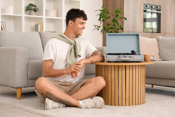 Young man with record player listening to music at home