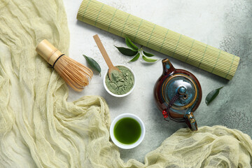Bowls of matcha tea and powder with chasen on grunge background