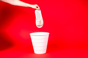 The slipper is thrown into the trash for disposal and recycling
