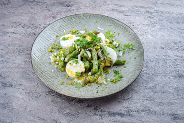 Traditional steamed green asparagus with goat cheese and pistachios served as a close-up on a...