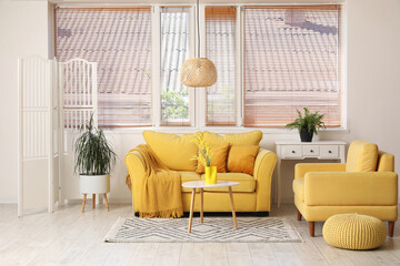 Interior of stylish living room with yellow sofa, coffee table and folding screen