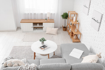 Interior of stylish living room with comfortable sofa, bench, coffee table and shelving unit