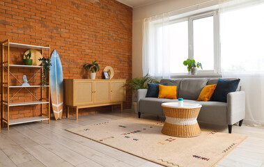 Surfboard, grey sofa and chest of drawers in beautiful living room