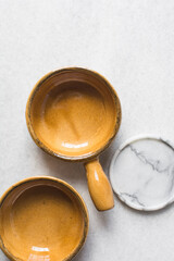 Top view of brown ceramic ramekins on a white marble countertop, terracotta ramekins with handles on a white background