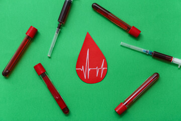Paper blood drop with cardiogram, blood samples and syringes on green background. World Blood Donor...