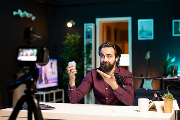 Tech expert looking at defective smart light bulb, trying to repair it while filming. Internet star hosting technology show, fixing broken IoT home automation product in neon lit studio