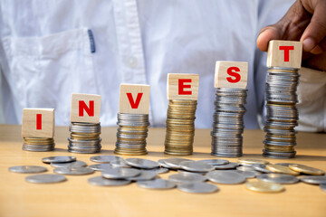 Invest word on wooden cube placed on pile of coin concept of investment on Stock market, mutual...