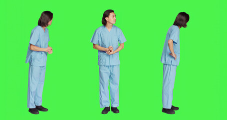 Over greenscreen wall, healthcare worker awaits for event, dressed in hospital protective outfit...
