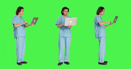Young nurse reading patient information on pc, using wireless computer before starting healthcare checkup at clinic. Man assistant working in medical industry, using laptop on greenscreen.