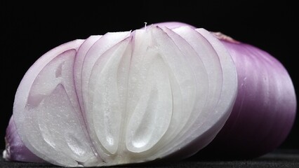 Macrography, the vibrant essence of fresh sliced red onion against a sleek black background takes...