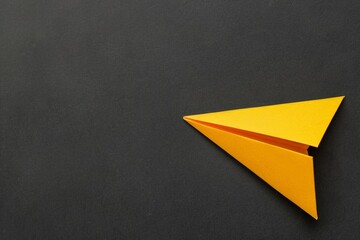 Yellow origami plane against a black background with copy space - business innovation, leadership skills, visionary thinking