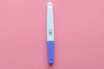 A white plastic pregnancy test is isolated over a pink background. Women's health, fertility, planning maternity and pregnancy concept. Test kits positive 2-line results. Copy space for advertising.