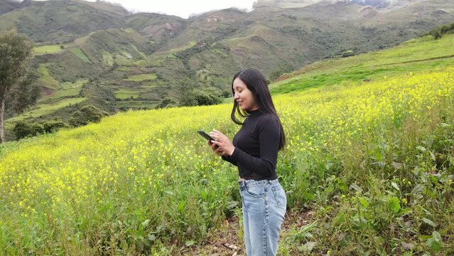 Contrastes florales entre la serenidad de las flores amarillas y la modernidad de una ni&ntilde;a con una camiseta negra y su tel&eacute;fono celular hablando, al aire libre, la tecnolog&iacute;a, la vida saludable, 