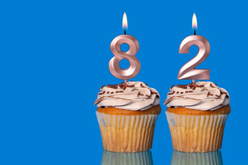 Birthday Cupcakes With Candles Lit Forming The Number 82.