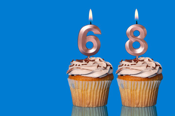 Birthday Cupcakes With Candles Lit Forming The Number 68.