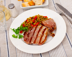 Appetizing roasted beef served with peas and peppers on platter
