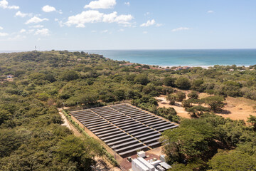 Solar Farm in Nicaragua, surrounded by trees and water. Ocean in the background of a solar park