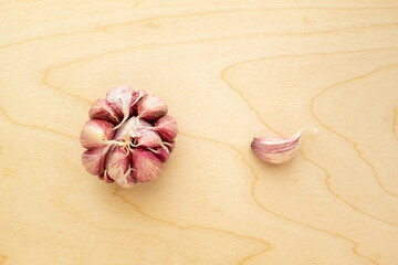 One garlic-bulb with one garlic-clove on wood background, top view. Garlic for publication, poster,...