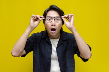 funny expression young asian man shocked happily opening mouth and lowering glasses. asian man with...
