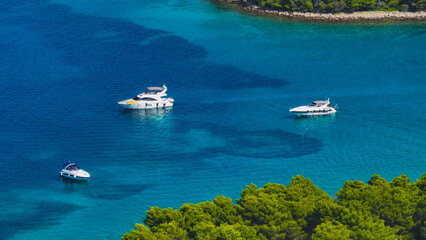 AERIAL: Flying above yachts and boats anchored in a secluded turquoise bay.