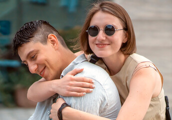 Two people walk in a city, a man and a young woman hugging and having fun together.