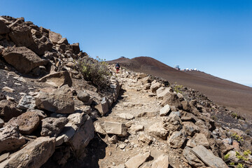 Woman hiking on trail up to the Pā Kaʻoao Overlook built by the Civilian Conservation Corps, active vacation in Haleakalā National Park, Maui, Hawaii
