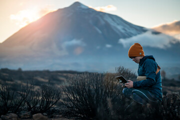 Girl is flying a drone in a beautiful area with mountains and volcanoes at sunset.