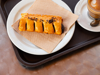 Simple and satisfying snack is prepared for visitor of cafe - large croissant with chocolate. Dish...
