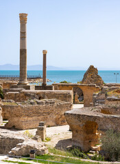 Sunlit Roman Baths of Antoninus ruins in Carthage on seashore, featuring remnants of marble...