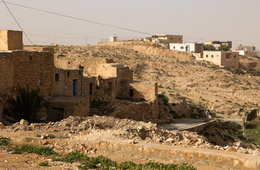 Sun-drenched weathered time-worn stone dwellings of Tamezret, ancient Berber hillside village in...