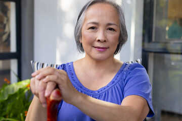 Outdoors, Asian middle-aged female in blue top, holding a cane