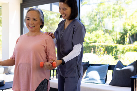 At home, Asian young female nurse and middle-aged patient practicing exercises