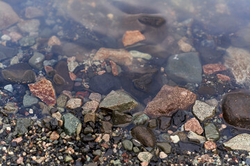 Stones of different textures and colors on the shore of the glacial lake