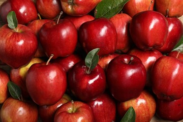 Fresh ripe red apples with leaves as background, closeup